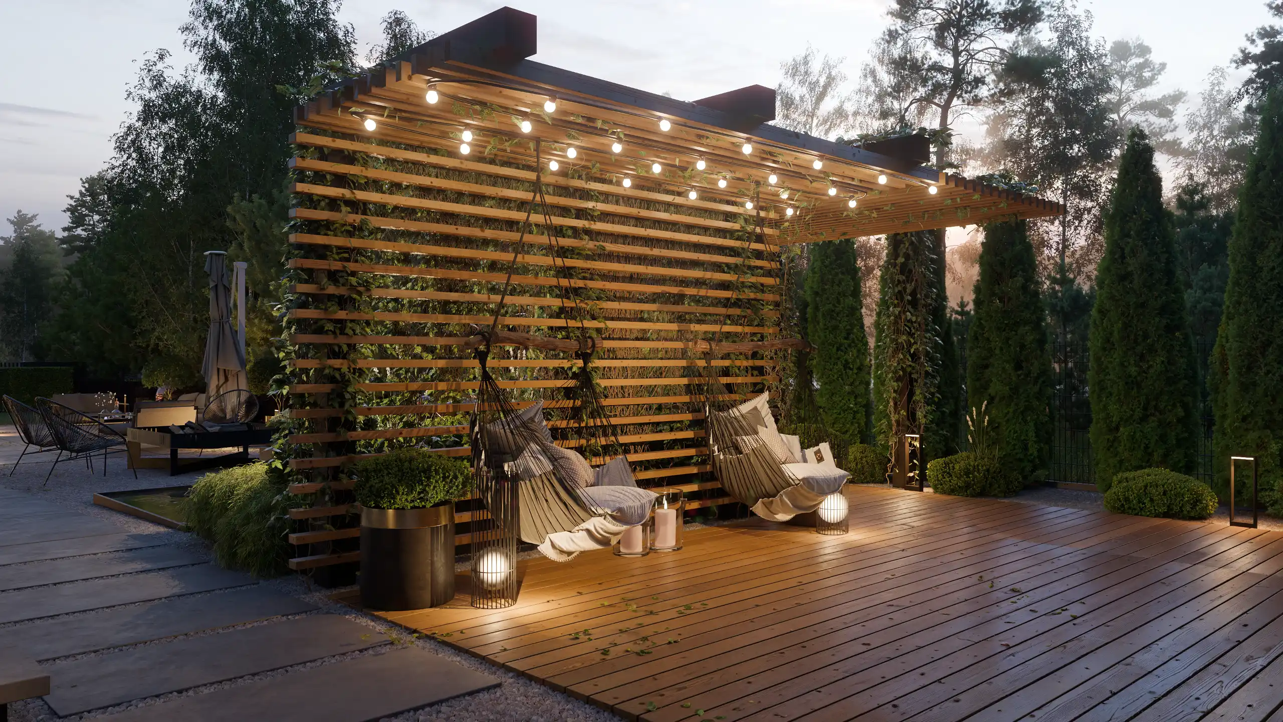 Klimatyczna strefa relaksu wieczorem z wiszącymi fotelami hamakowymi i girlandami świetlnymi żarówkami. Projekt tarasu z drewnianą ścianą ażurową, pergolą porośniętą bluszczem i oświetleniem ogrodowym – NAIMAD STUDIO.